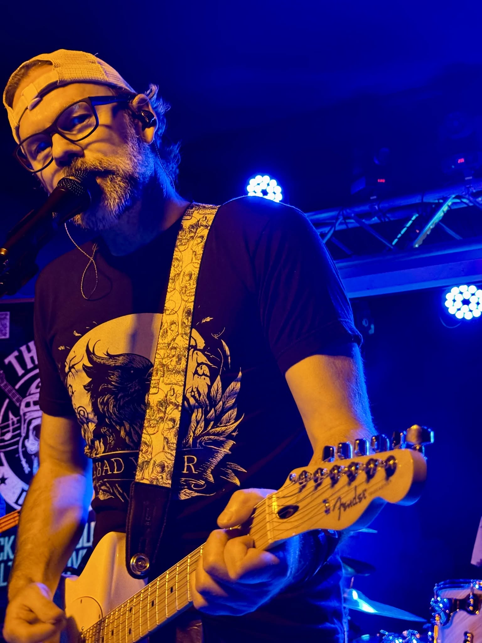 Mike singing and playing guitar under blue stage lights