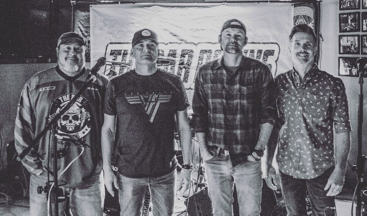 An early black-and-white band photo in front of The Bar Downs banner