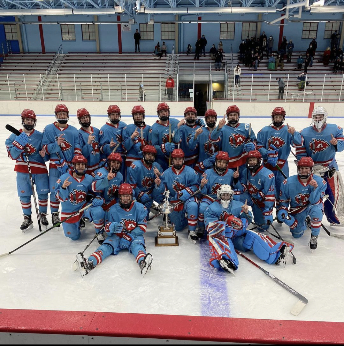 The high school hockey team gathered on the ice with a trophy
